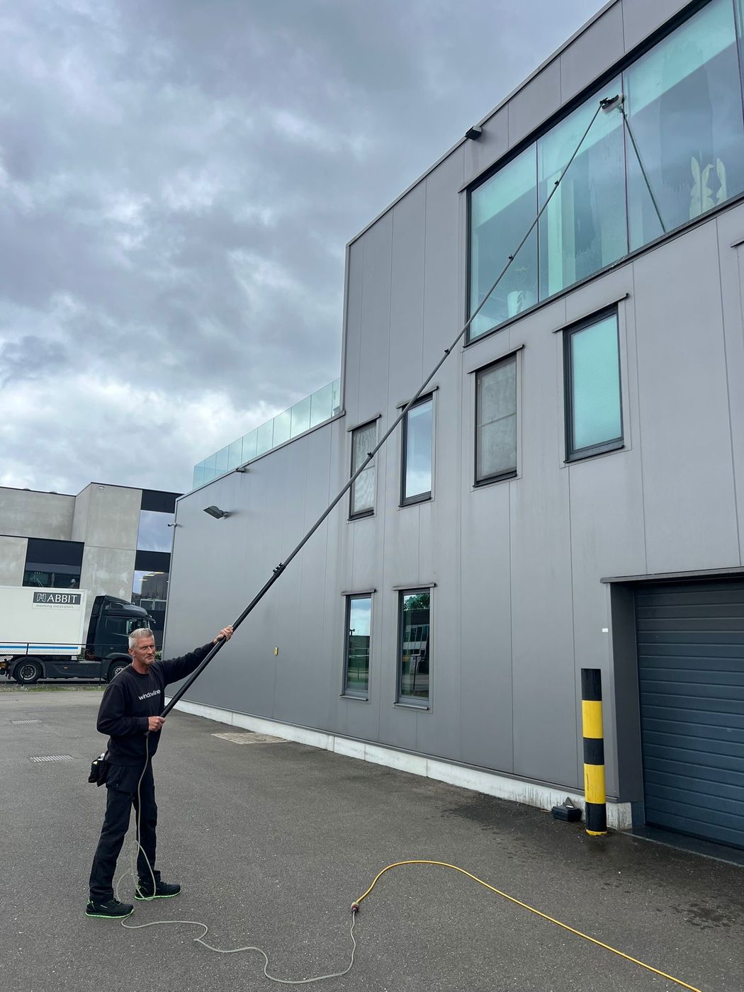 Hoge bedrijfsgevel reinigen met telescoopsteel zonder ladder